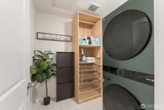 Convenient laundry area with full-size stacked washer and dryer and built-in shelving.
