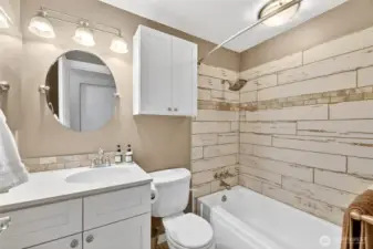 HALL BATHROOM – Remodeled 2018  Wood Shaker style cabinets with Quartz countertop and undermount sinks  Tub with Silver Travertine surround  Ceramic barn tile