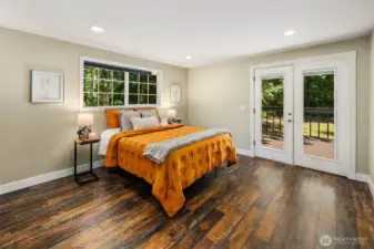 Spacious primary bedroom has doors directly onto the deck