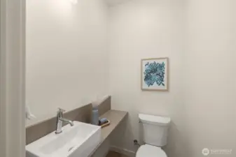 A thoughtfully designed powder room with sleek finishes, offering a blend of functionality and modern style. Photos of home with similar layout, finishes & fixtures.