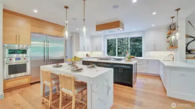 At the heart of the home, the chef’s kitchen is a showpiece of style and functionality, with fresh white cabinets, gleaming quartz countertops, white oak accents, floating shelves and champagne bronze hardware.