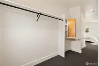 Primary walk-in closet area with built in ironing board station.
