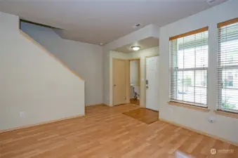 The living area offers a view toward the entry, highlighted by large windows that fill the space with natural light. The conveniently located powder room on the lower level adds to the home's functionality.