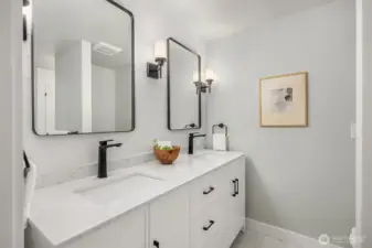 The recently updated bathroom features shiplap wall detail, dual sink vanity, new flooring and new shower with glass door.