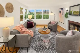 Stunning living room is full of natural light. There is a wood burning fireplace and a serene outlook to your gorgeous backyard.