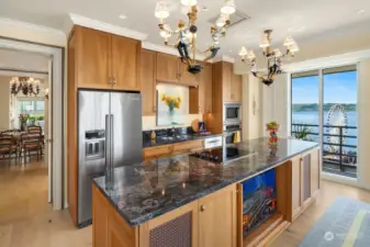 Kitchen has 10' prep island, custom cabinetry, slab granite countertops, double sinks, electric cooktop, wall oven and convection oven and space for dining.