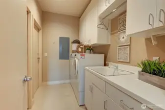 Laundry room with ample cabinets, laundry sink and walk-in closet for extra storage. Door leads to back stairwell.