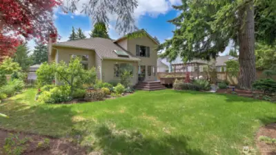 The fully enclosed backyard features an expansive lawn, perfect for hosting gatherings and events, while offering exceptional privacy amidst lush, verdant landscaping