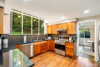 A striking greenhouse window frames views of the manicured backyard, filling the space with sunlight—perfect for morning coffee,  weekend brunches, or casual entertaining.