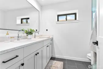 Double sink vanity, tiled floors and tiled shower.