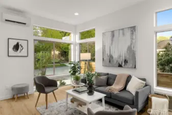 Step into a sun-filled living space where oversized windows, warm wood flooring, and soaring ceilings create an inviting atmosphere.