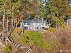 Stunning west-facing waterfront home nestled among Madrona trees, featuring multiple view decks and direct access to the shoreline below.