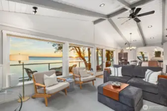 Inviting living area with expansive windows and deck access, blending indoor comfort with outdoor waterfront living on San Juan Island.