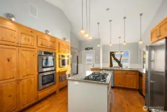 Well-appointed kitchen with custom cabinetry, double ovens, and generous prep space overlooking the open dining area and water beyond.