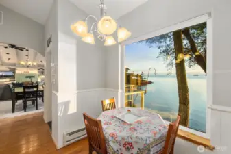 Charming breakfast nook framed by picture windows offering peaceful shoreline views—perfect for morning coffee by the sea.