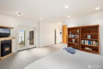 Serene primary suite with fireplace and deck access, creating a peaceful sanctuary above the shoreline.