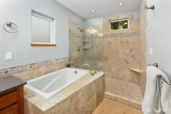 Beautifully appointed soaking tub and oversized walk-in shower with timeless stone finishes elevate everyday relaxation.