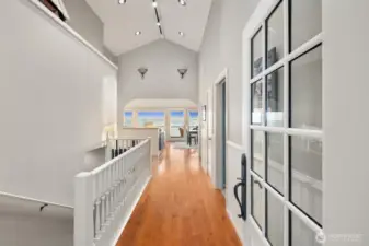 Welcoming entry with vaulted ceilings and warm wood floors opens toward a light-filled great room with expansive waterfront views at this Smugglers Cove retreat in Friday Harbor.