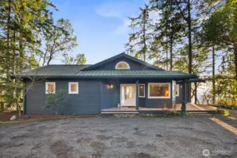 Inviting covered entry framed by evergreen surroundings, blending refined coastal design with the tranquility of San Juan Island living.