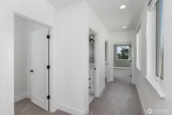 The second level hallway with the second bedroom to the left, then the full bath, the utility room and the door to the primary bedroom.