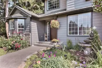 This captivating photograph beautifully captures the essence of an "Inviting Front Entry," highlighting a stunning display of a "Colorful garden" enhanced by a serene "water feature." The image showcases a vibrant and lush garden setting, complemented by a tranquil water element, which together create a peaceful and welcoming outdoor environment, perfect for any prospective homeowner to envision themselves enjoying.