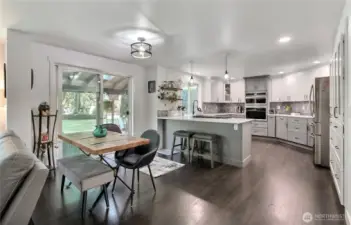 This photo showcases the inviting eat-in kitchen area, providing a clear view of the functional kitchen eating bar, the stylish cabinetry, and the seamless transition to the covered deck via the convenient sliding glass door, highlighting the property's comfortable and connected living spaces.