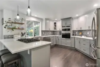 This photo offers a different perspective, highlighting the well-lit and spotless kitchen, specifically emphasizing the window that provides inviting views of the outdoor deck area.