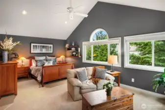 Spacious primary bedroom with vaulted ceilings and wall of windows.