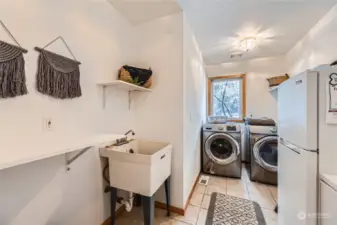 Designed for efficiency, this spacious laundry area includes a utility sink and built-in shelving, making chores a breeze.