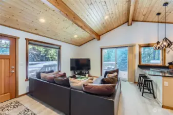 The spacious ADU living room boasts beautiful tongue-and-groove ceilings and a sliding door that opens to a wrap-around porch, perfect for enjoying the peaceful surroundings.