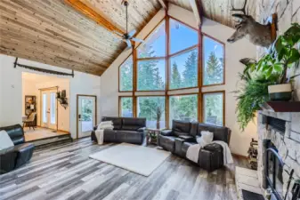 The living room’s breathtaking wall of windows brings the outdoors in, filling the space with natural light and offering stunning views of the surrounding landscape in every season.