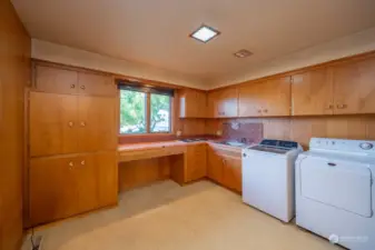 The laundry room features an abundance of cabinets and along with a cooktop for canning and a utility sink.