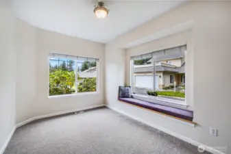 This office or bonus room located near the home’s entrance features large windows, plenty of natural light, and views of the mature landscaping surrounding the front of the home.