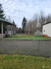 Green space for pets between enclosed shop and covered RV/carport area.