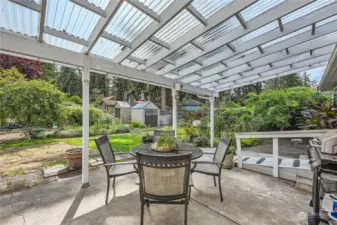 View to back patio and 3 sheds that stay for ample storage! Also view of pear trees and garden areas