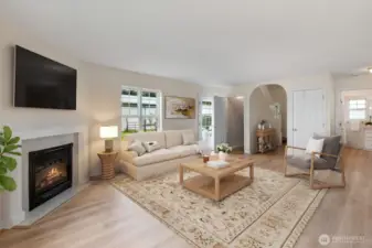 Virtually staged living room with natural light streaming in.  New LVP flooring and a cozy gas fireplace.