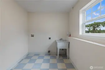 The cheery laundry room with utility sink also has a water closet to the left. Convenient access to outside provides quick clean ups before heading to the main floor.