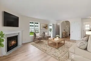 Virtually staged living room with natural light streaming in.  New LVP flooring and a cozy gas fireplace.