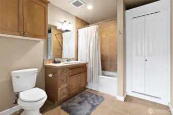 The Primary full bath has a tiled vanity with a tiled bath/shower combination creating a cohesive and modern look.  A dedicated linen closet offers practical storage space and a custom built-in cabinet for all those items you need but never have enough space.