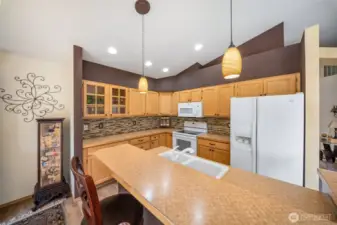 Kitchen features lighted glass display cabinets and full height tile backsplask