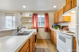 The galley kitchen features plenty of lovely wood cabinetry, ample countertops & lots of counter space