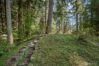 Another inviting perspective from the home showcases the expansive lot, complete with a stairway leading to a desirable level area—ideal for a garden retreat, outdoor entertaining space, or future possibilities tailored to your vision.