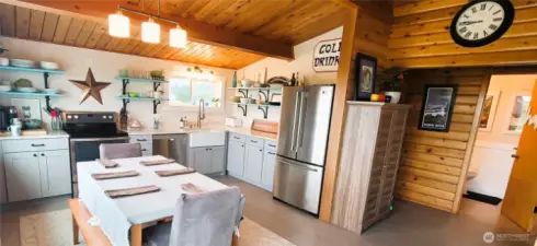 A bright and welcoming kitchen where coastal charm meets functionality, featuring quartz counter tops, a farmhouse sink, cozy dining, SS appliances and stunning ocean views for the perfect gathering spot.