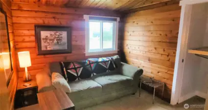 A tranquil private sitting room offering a cozy retreat, seamlessly leading into the expansive primary suite. Warm wood tones and thoughtful design create an inviting space for relaxation and quiet moments.