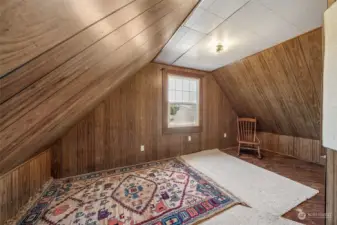 Partially finished attic where you'll find a cozy reading nook, the perfect hideaway for those who enjoy getting lost in a good book. With natural light streaming through the windows overlooking Clark's Creek, the backyard & deck. This peaceful retreat offers a quiet space for reflection or relaxation. Current seller used this as an office space. To the left of this photo is additional attic storage space.