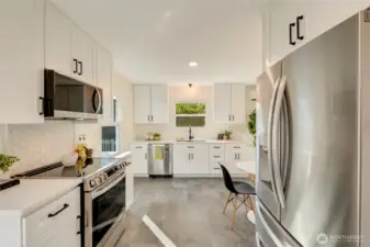 Kitchen with quartz countertops and a tile splash guard behind the range.