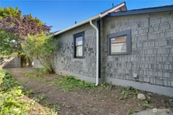 Notice the fresh stain, fresh trim paint, brand new gutters and downspouts. A side yard extends along the west side of the building.