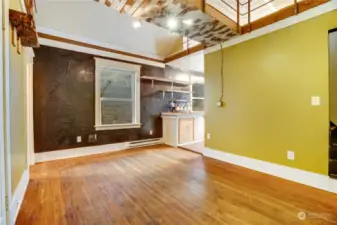 Fir floors cover the living room, front hall, and bedroom. Stairs on the right lead up to the loft.