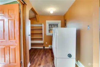 A pantry area offers additional storage just beyond the washer and dryer.