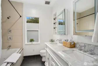 This spa-like bathroom offers a marble countertop vanity, double shower, spa tub, tile surround, and tiled floors.